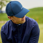 Man wearing a navy blue cap and jacket on a grassy field