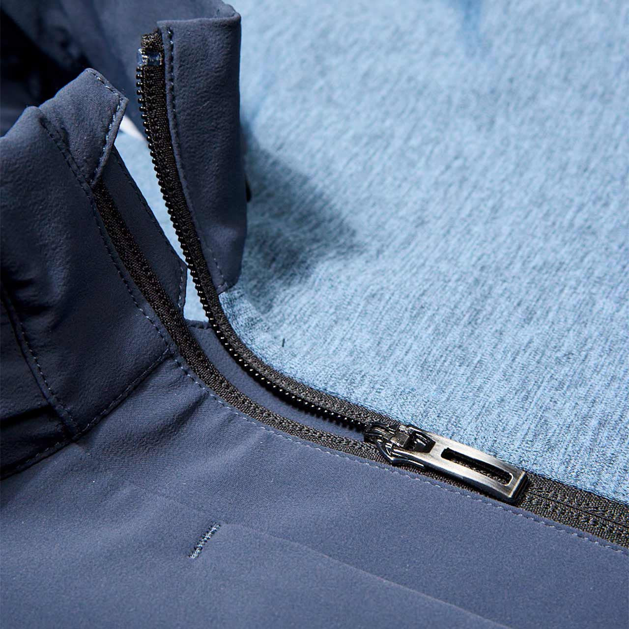 Close-up of a zipper on a blue jacket with a textured fabric background.