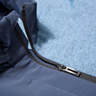 Close-up of a zipper on a blue jacket with a textured fabric background.