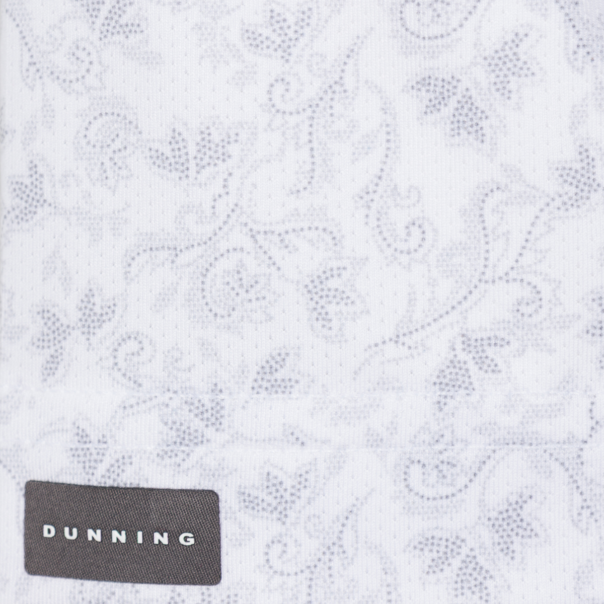 Bennett Ventilated Performance Polo grey botanical print on white fabric with Dunning label, close-up